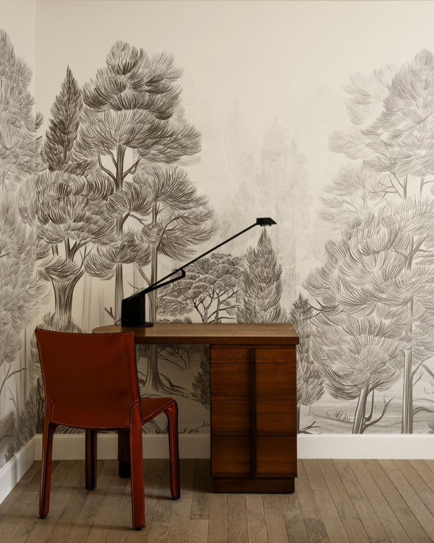 Room with a wooden desk and red chair against a wall with tree mural.