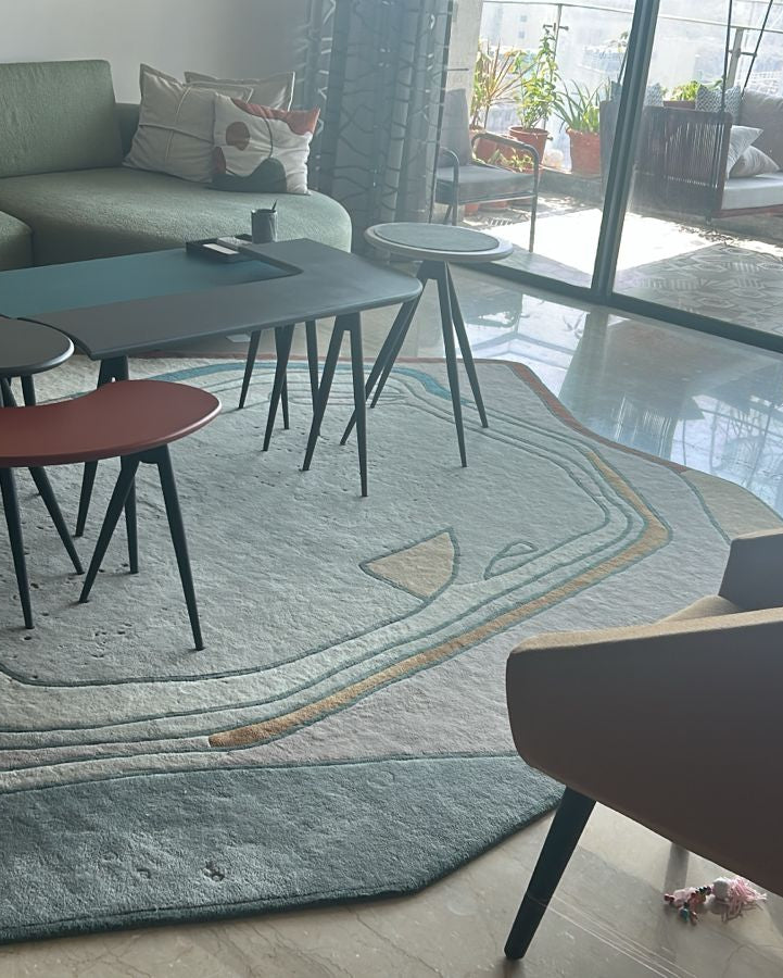 Modern living room with a gray sofa, round tables, and chairs.