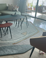 Modern living room with a gray sofa, round tables, and chairs.